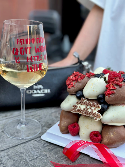 Chocolate dipped strawberry cube with glass of wine and bag on the background
