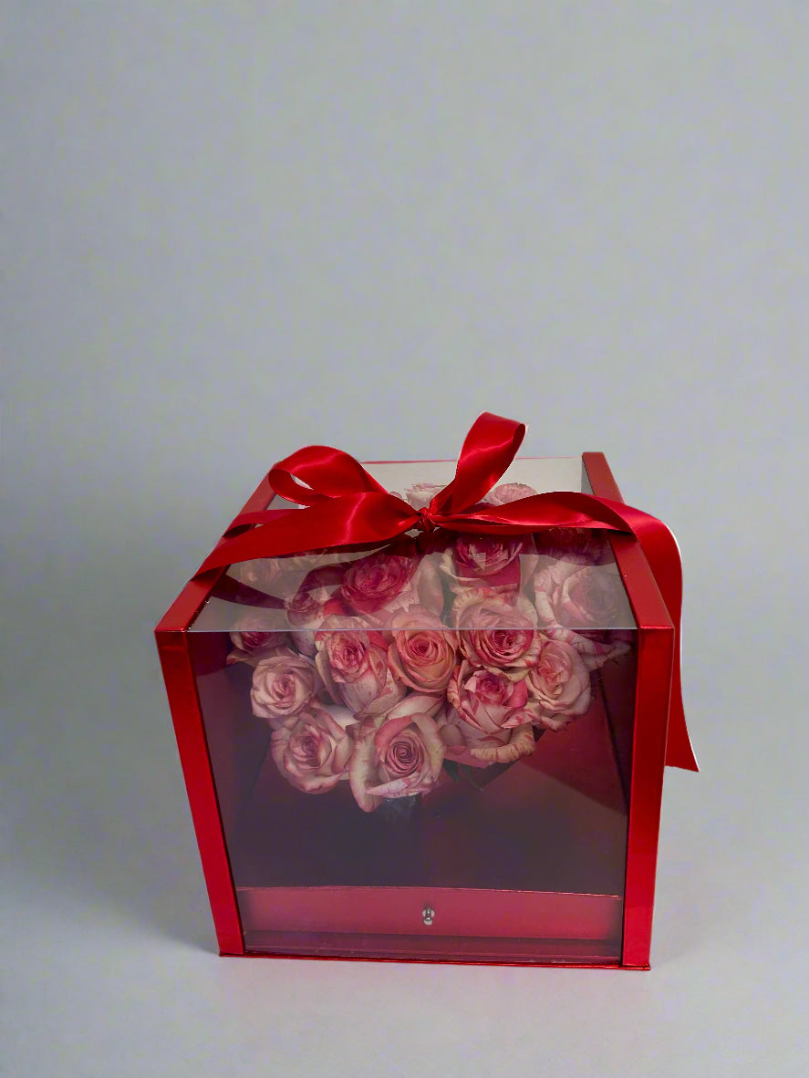 red gift box with roses, clear lid and ribbon on top