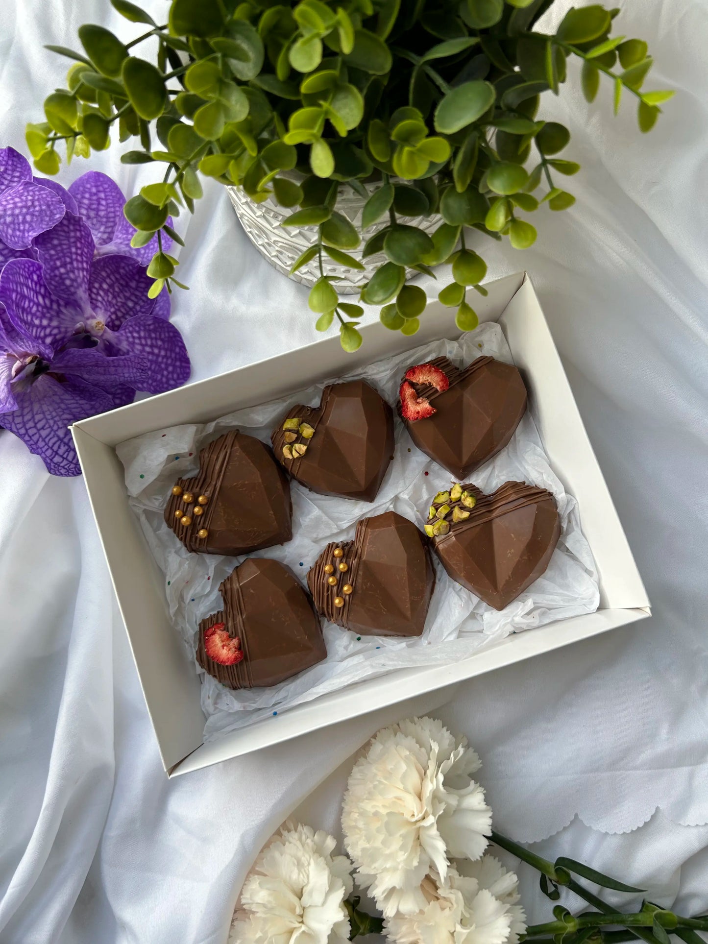 6 heart shaped dubai kunafa chocolate bars with flowers on the background 